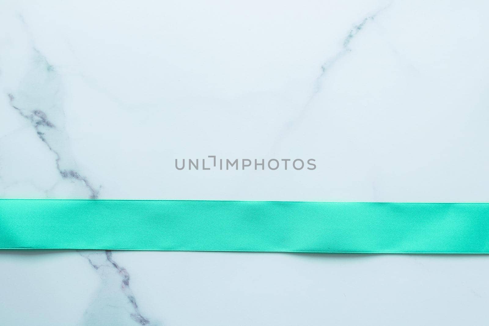 Green silk ribbon on marble background, top view by Anneleven