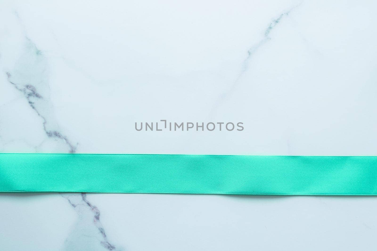 Holiday design, greeting card and vintage gift concept - Green silk ribbon on marble background, top view