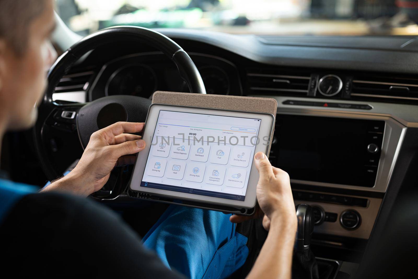 Automotive mechanic running diagnostics software on tablet. Unrecognizable vehicle service manager worker work in mechanics garage, check and maintenance to repair the engine car in workshop by uflypro