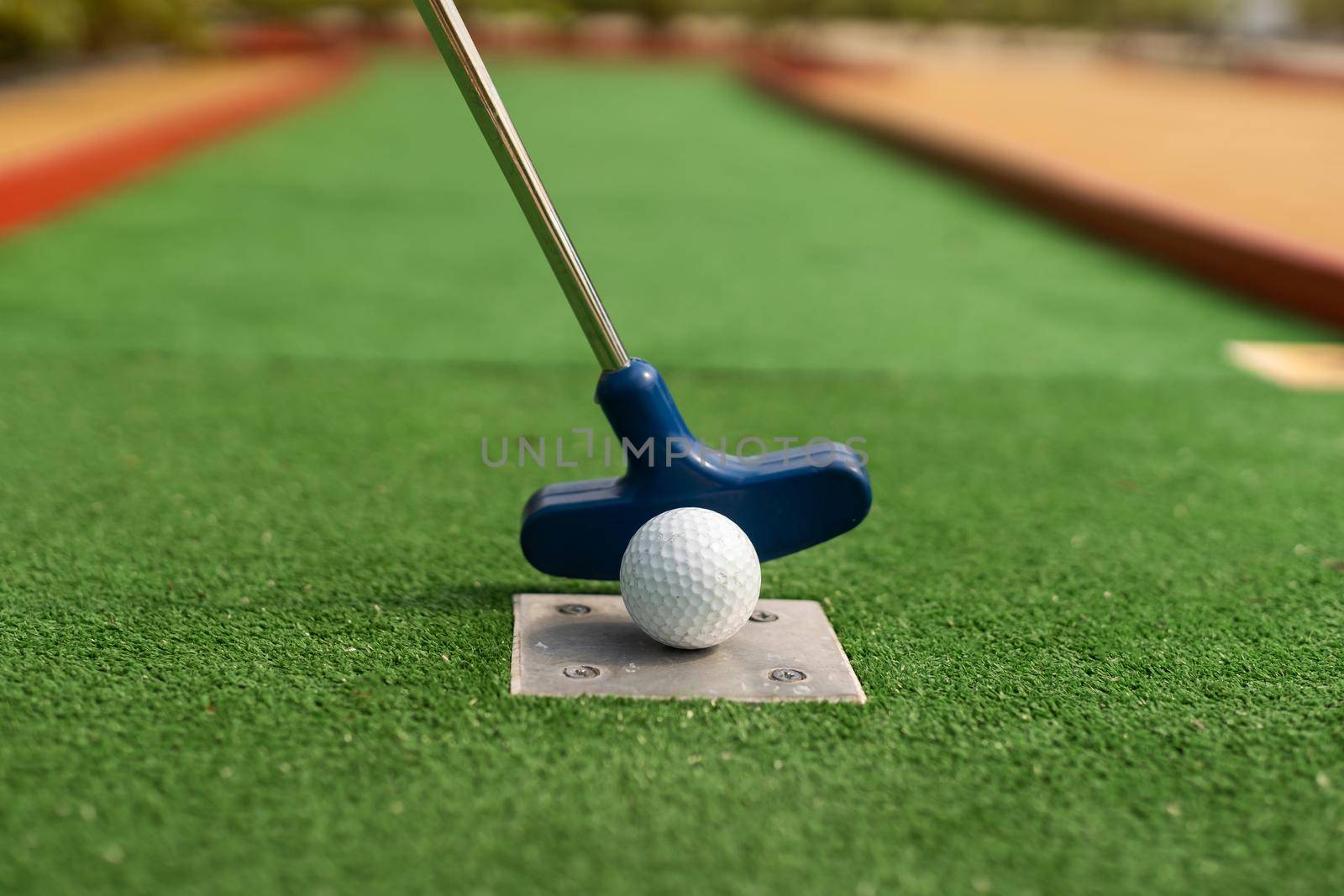 A club prepares to hit a ball during a mini golf game.