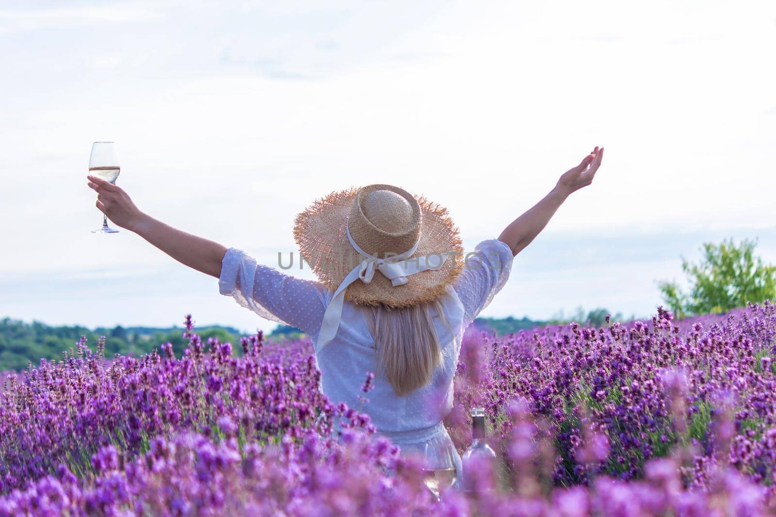 a girl in a lavender field pours wine into a glass. Relaxation. selective focus