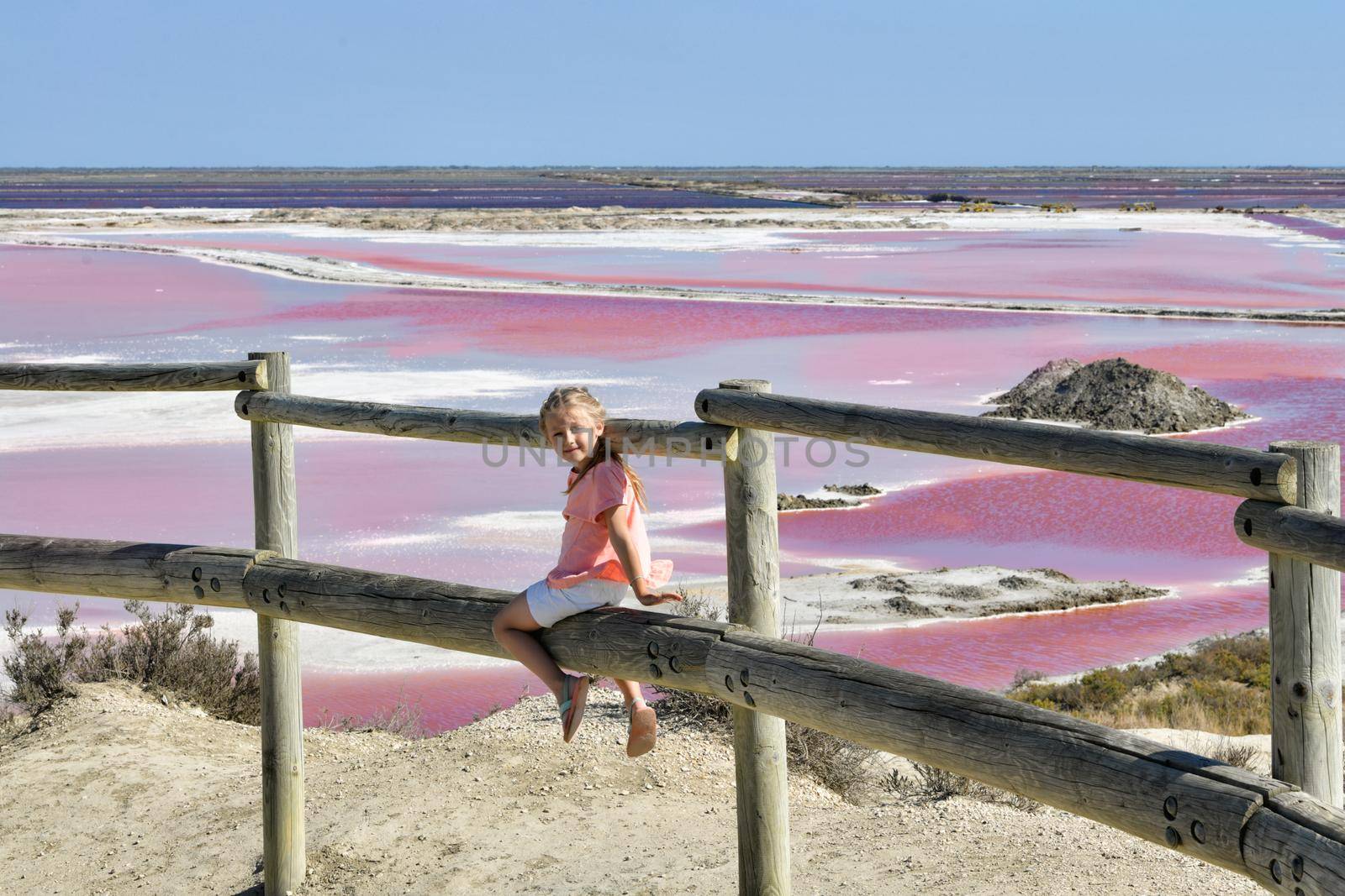 A girl at the Salin-de-Giraud salt farm with pink purple salty water