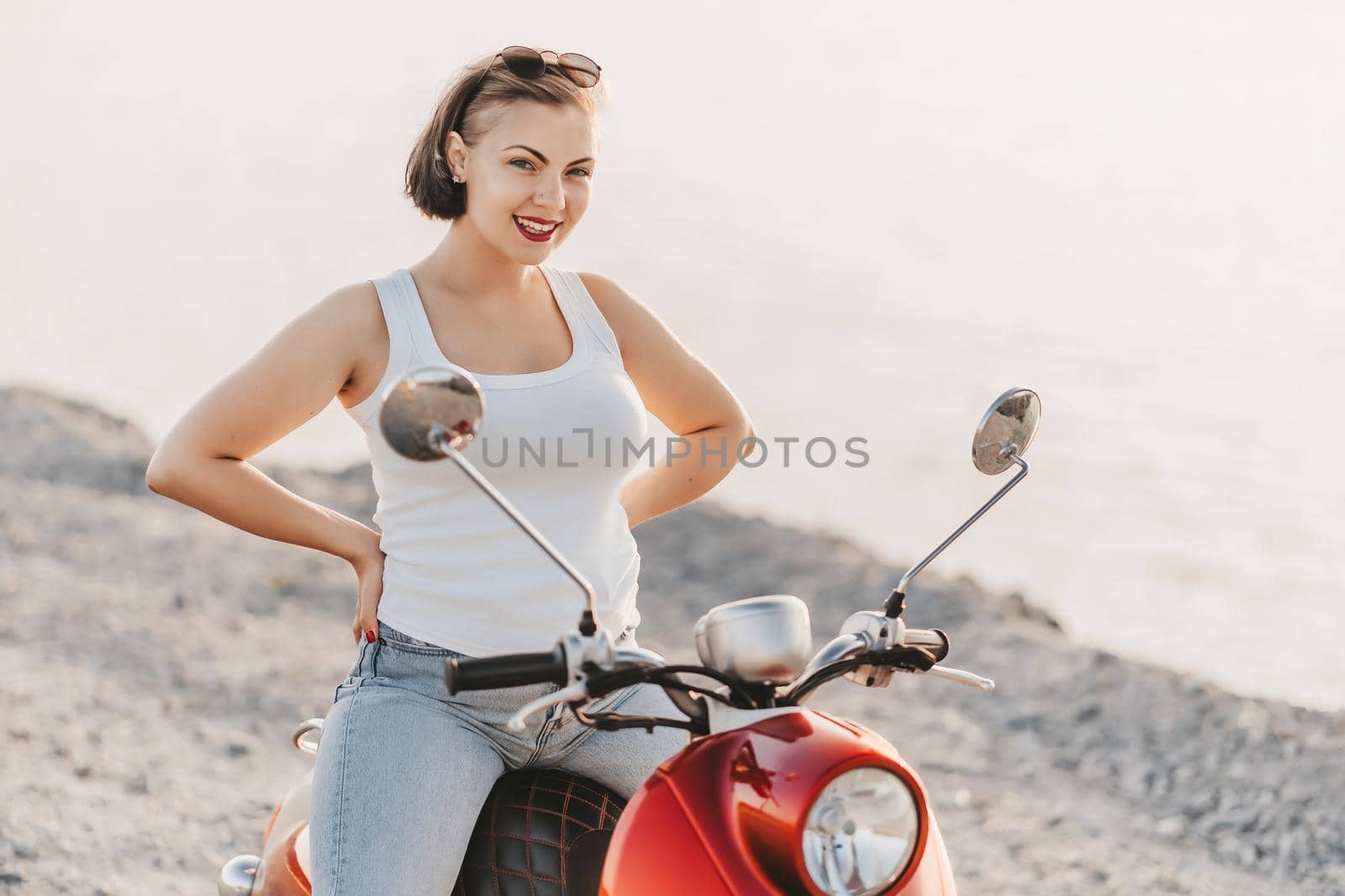 Young pretty woman's portrait. Girl sitting on red retro scooter at nature background. High quality photo