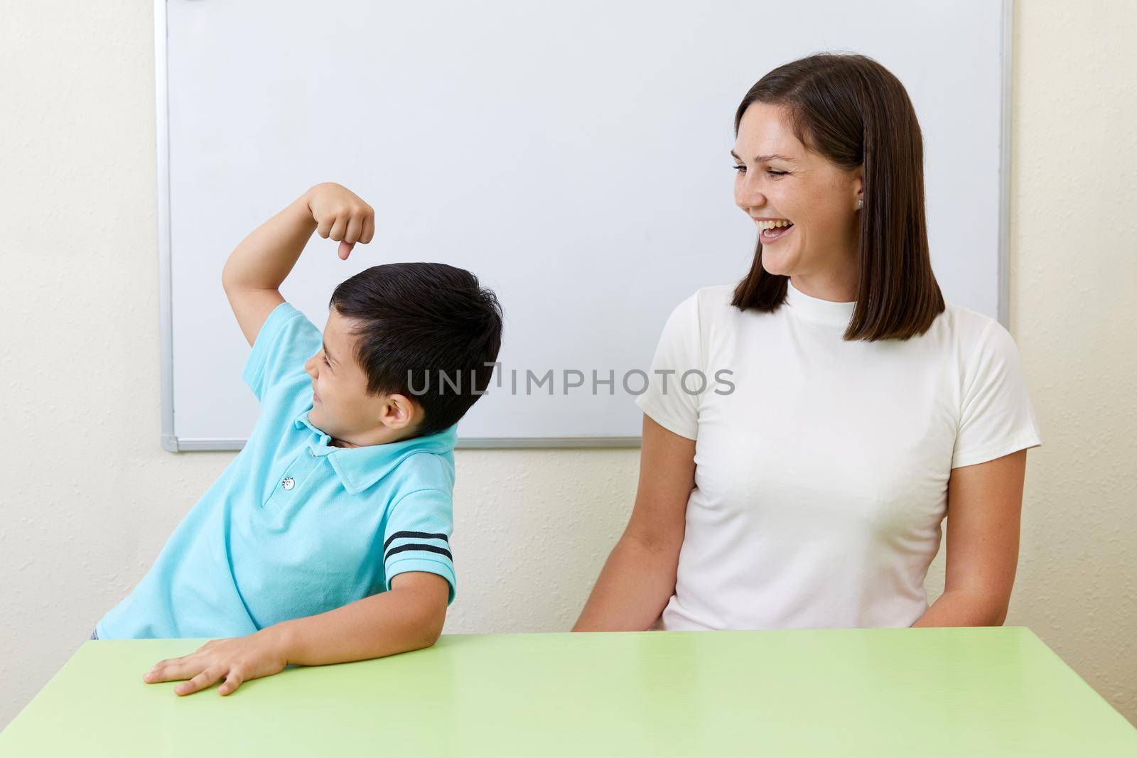 Boy is showing his arm muscles to his preschool teacher
