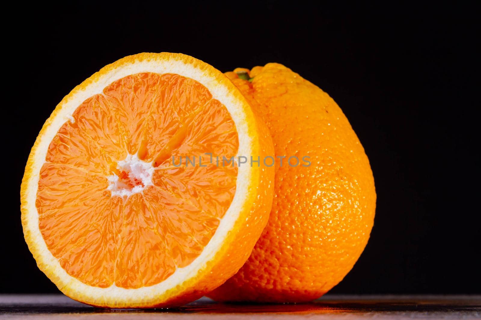 Half an orange. Two halves of fruit on a wooden table. Fresh and ripe fruit is cut on a dark background. Copyspace.