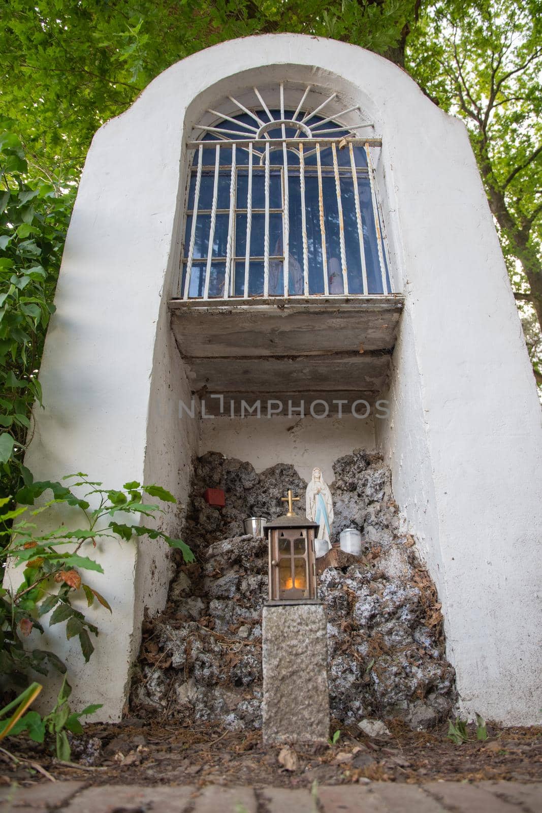 a chapel for prayers in the middle of the forest a figurine of St. Mary, a grotto for lighting candles a bench stands opposite, this is a place for solitude and reflection. High quality photo