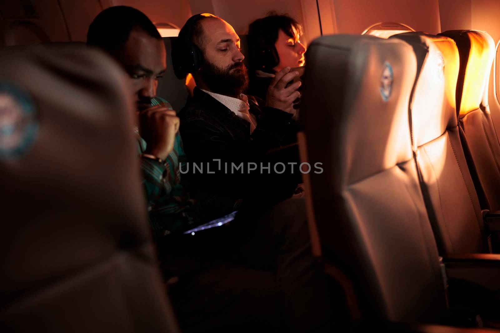 Diverse passengers flying in economy class with airplane jet, using international airways service on commercial flight. Group of people travelling by plane to go to holiday destination or job trip.