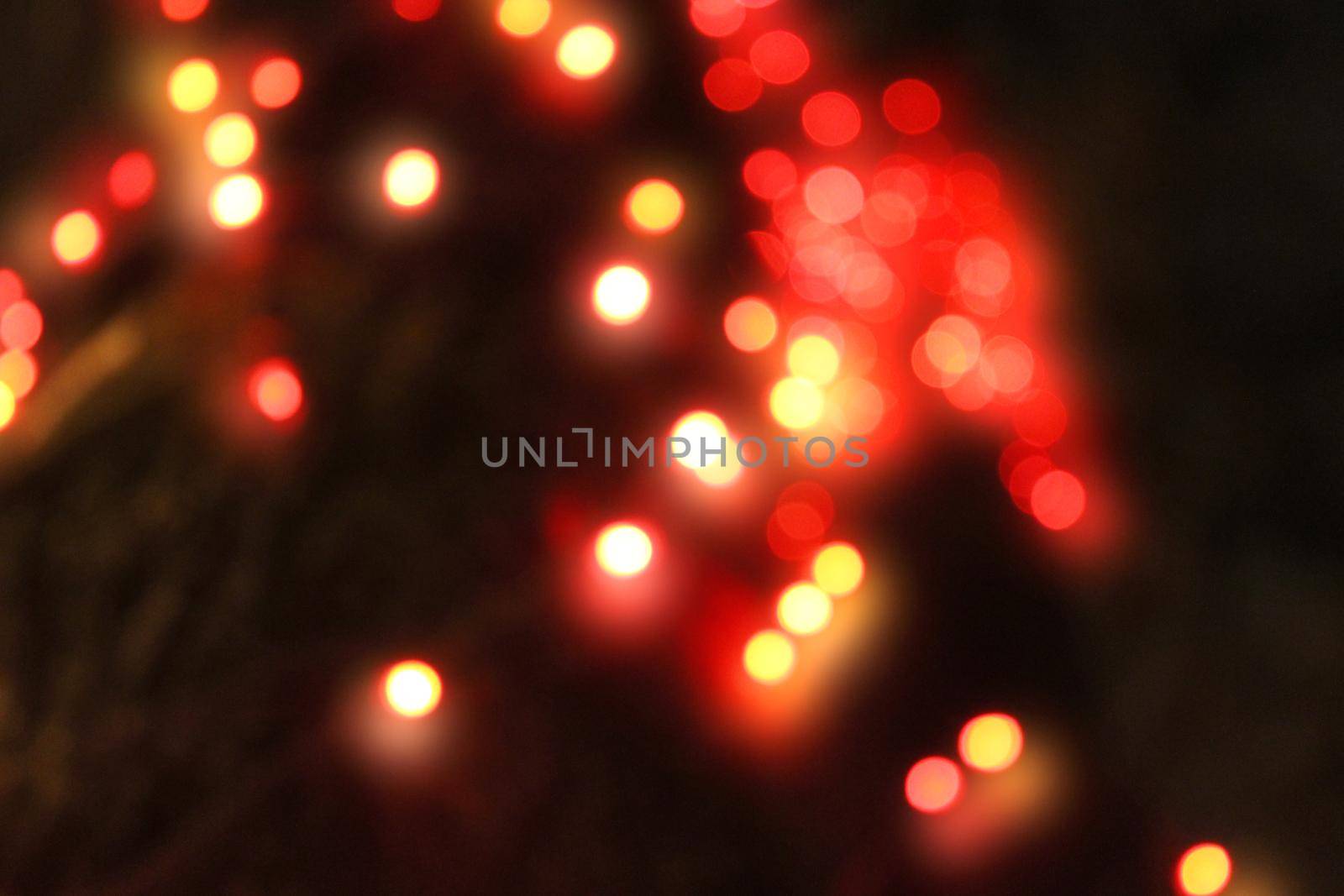 Red Christmas garland blurred and defocused with bokeh on a dark background