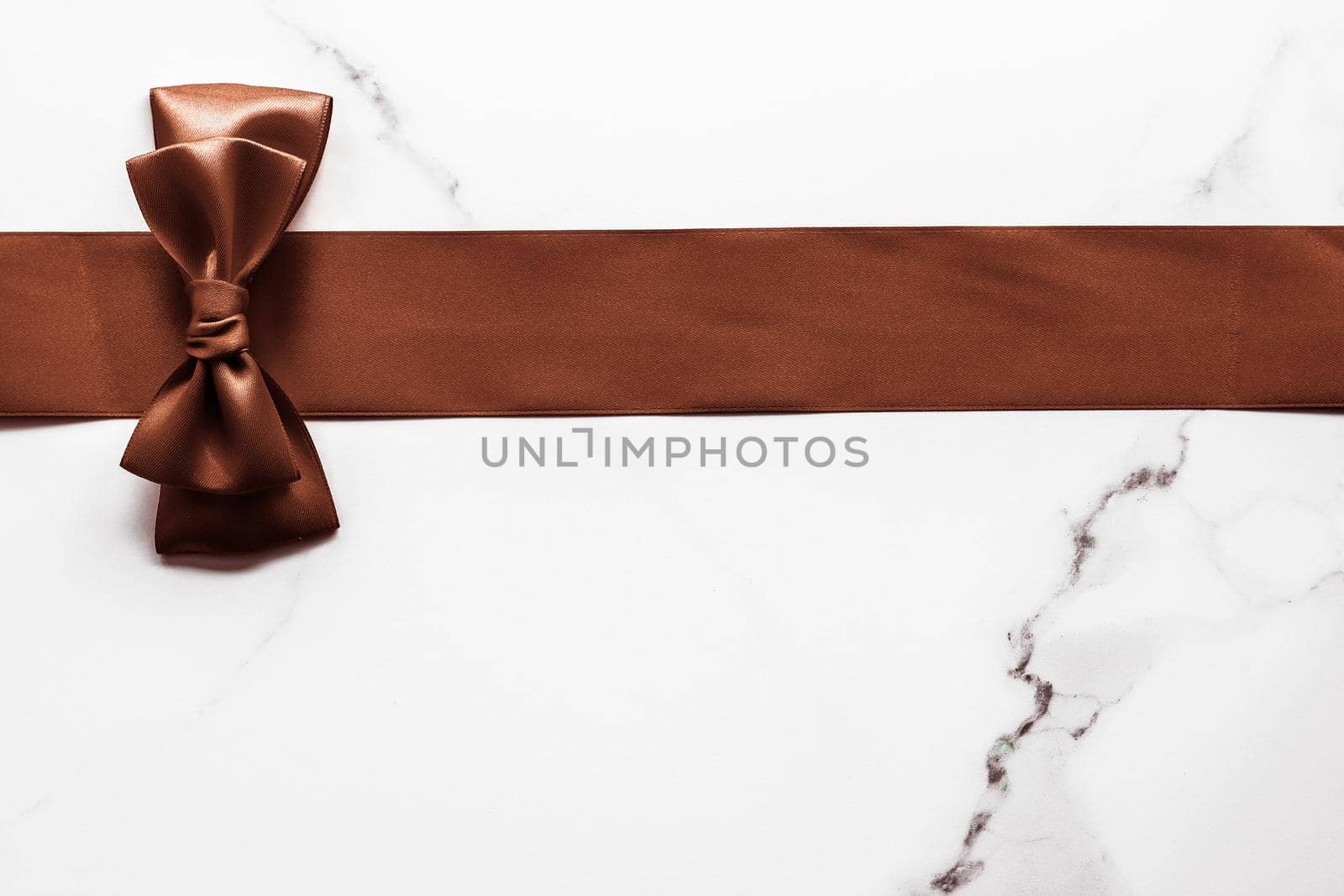 Holiday gift, decoration and sale promotion concept - Chocolate brown silk ribbon on marble background, flatlay