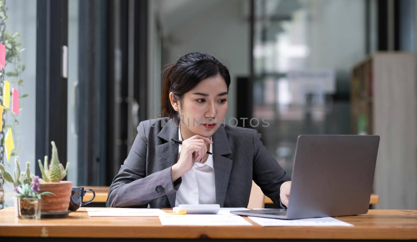 Asian Businesswoman working on laptop at her desk at the office. by wichayada