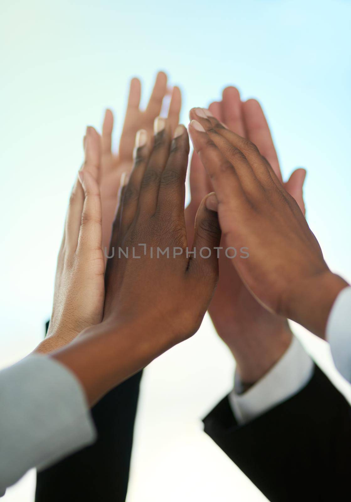 Team number one. a group of businesspeople giving each other a high five outdoors. by YuriArcurs