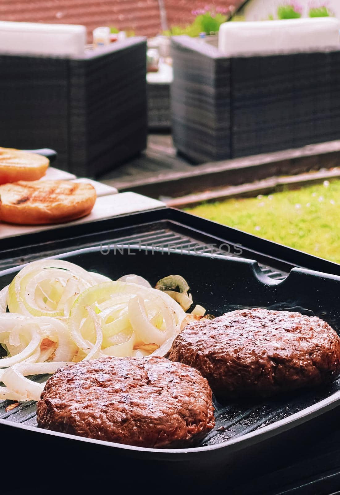 Cooking minced beef burger on cast iron grill skillet outdoors, red meat on frying pan, grilling food in the garden, English countryside living concept