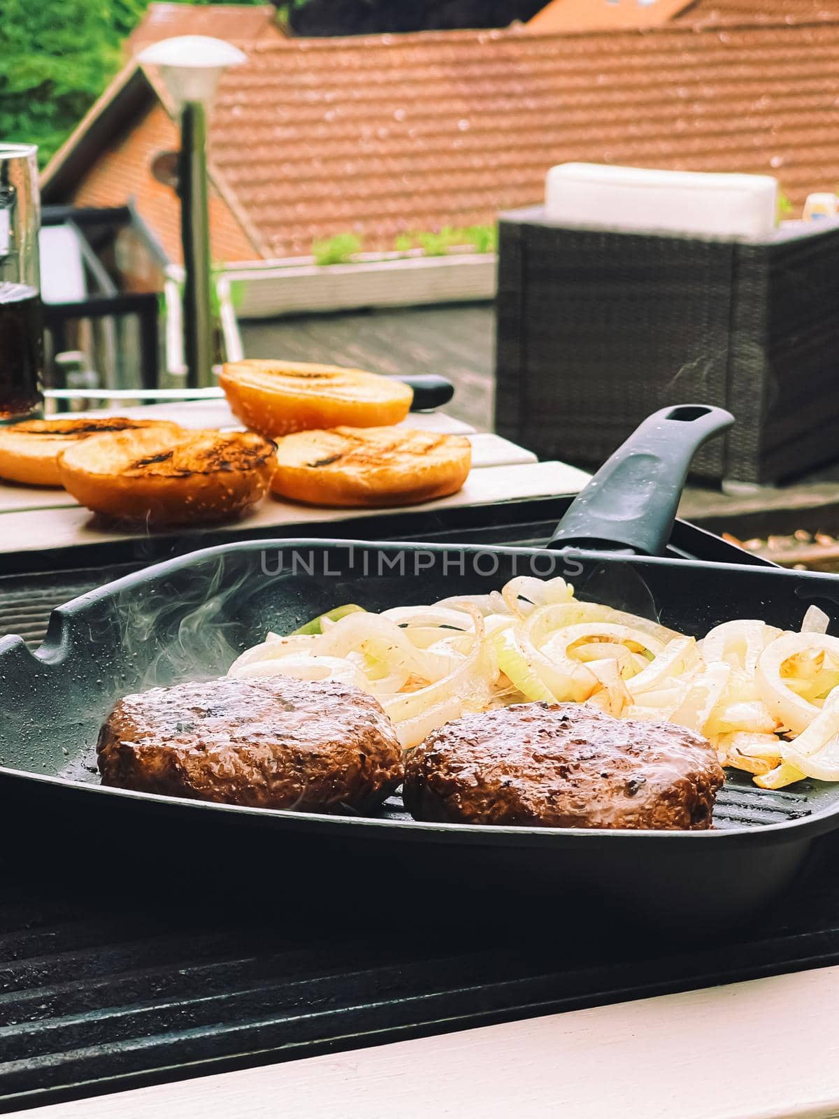 Cooking minced beef burger on cast iron grill skillet outdoors, red meat on frying pan, grilling food in the garden, English countryside living concept