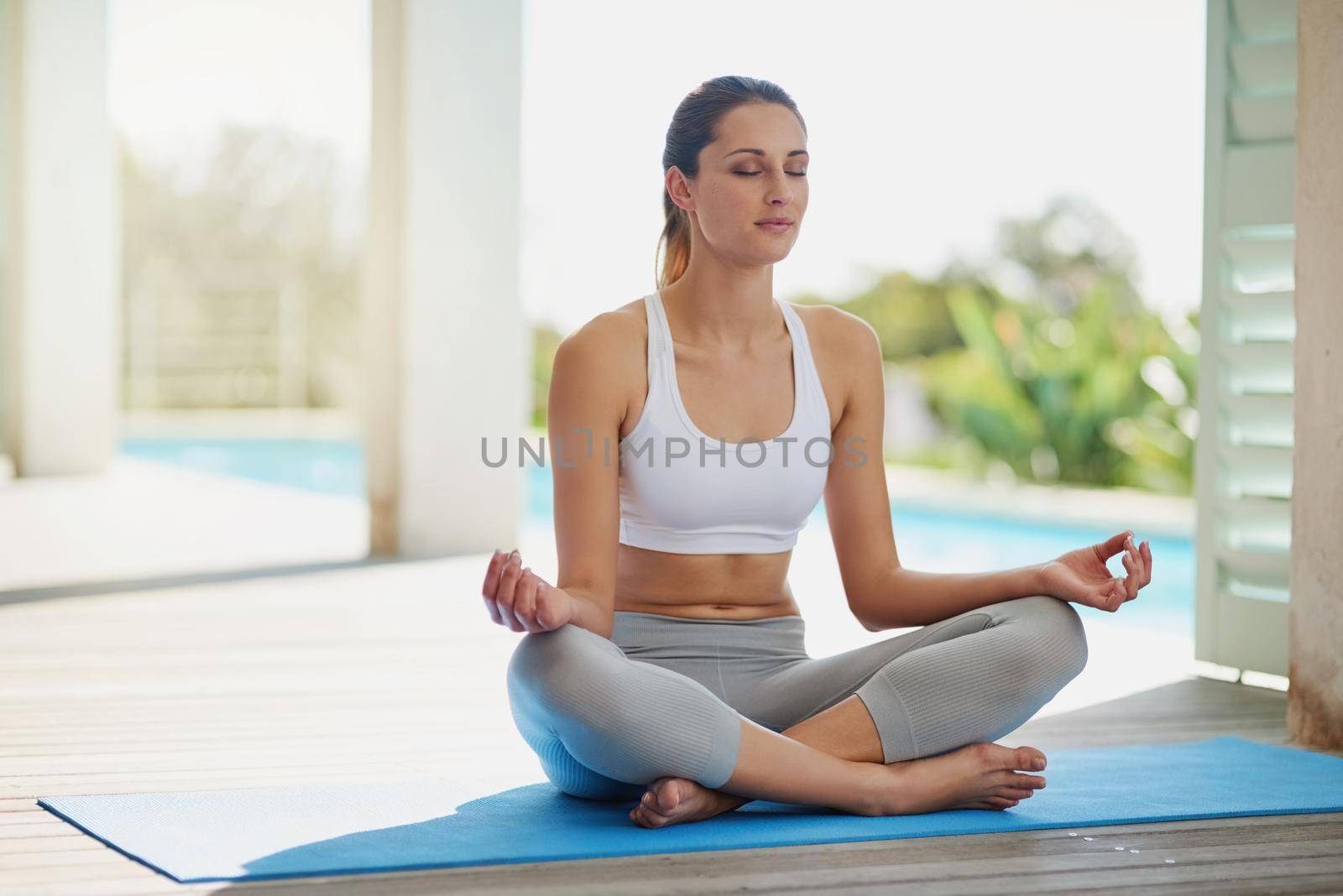 Finding her center. an attractive young woman meditating on her patio