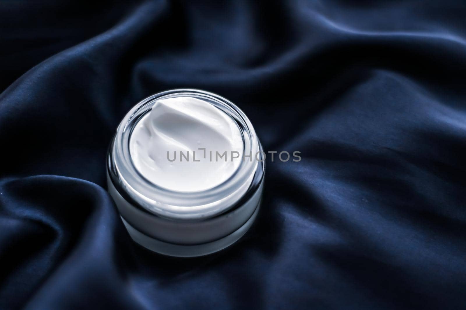 Luxury face cream jar on a dark blue silk by Anneleven