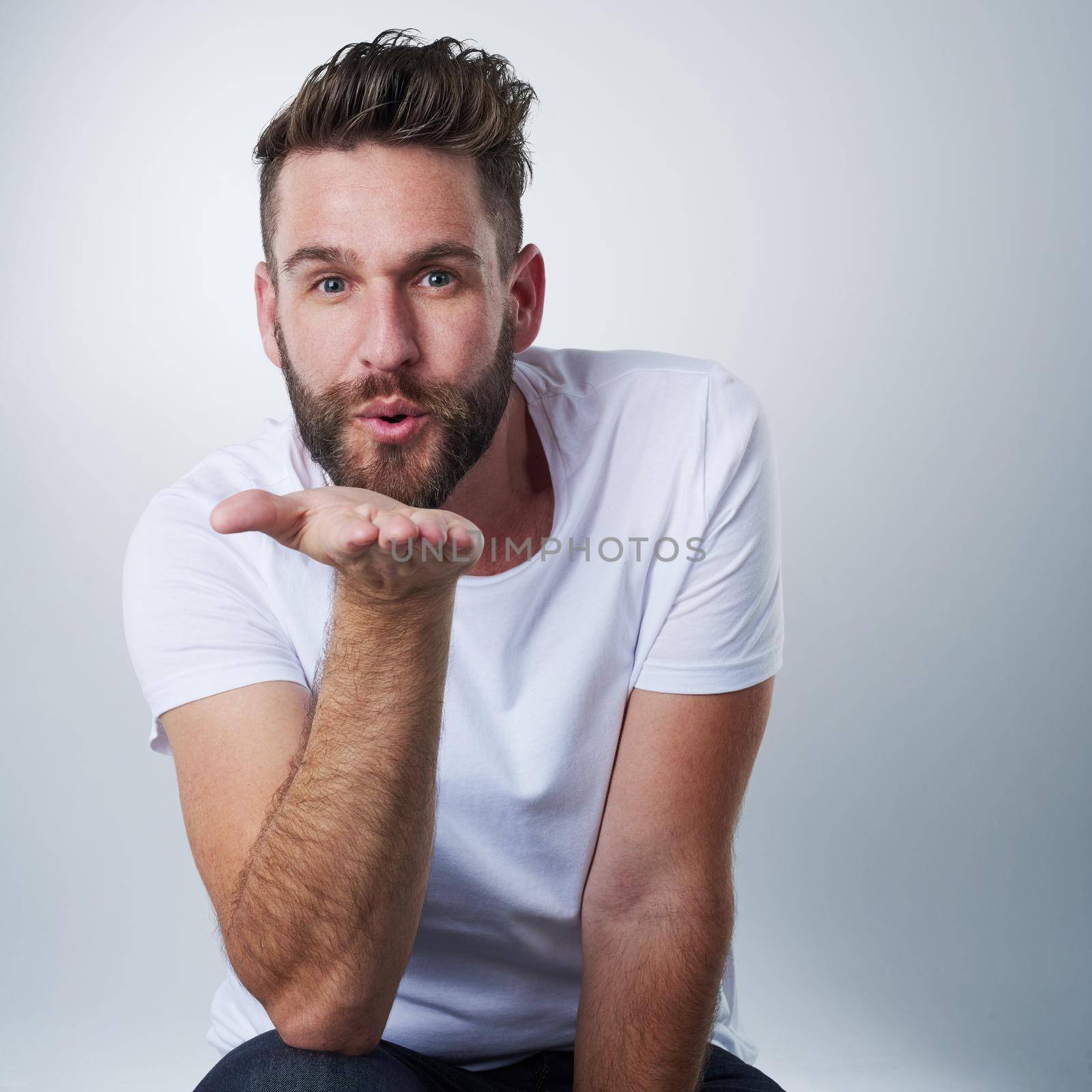 Kisses coming your way. Portrait of a sweet young man blowing a kiss in studio