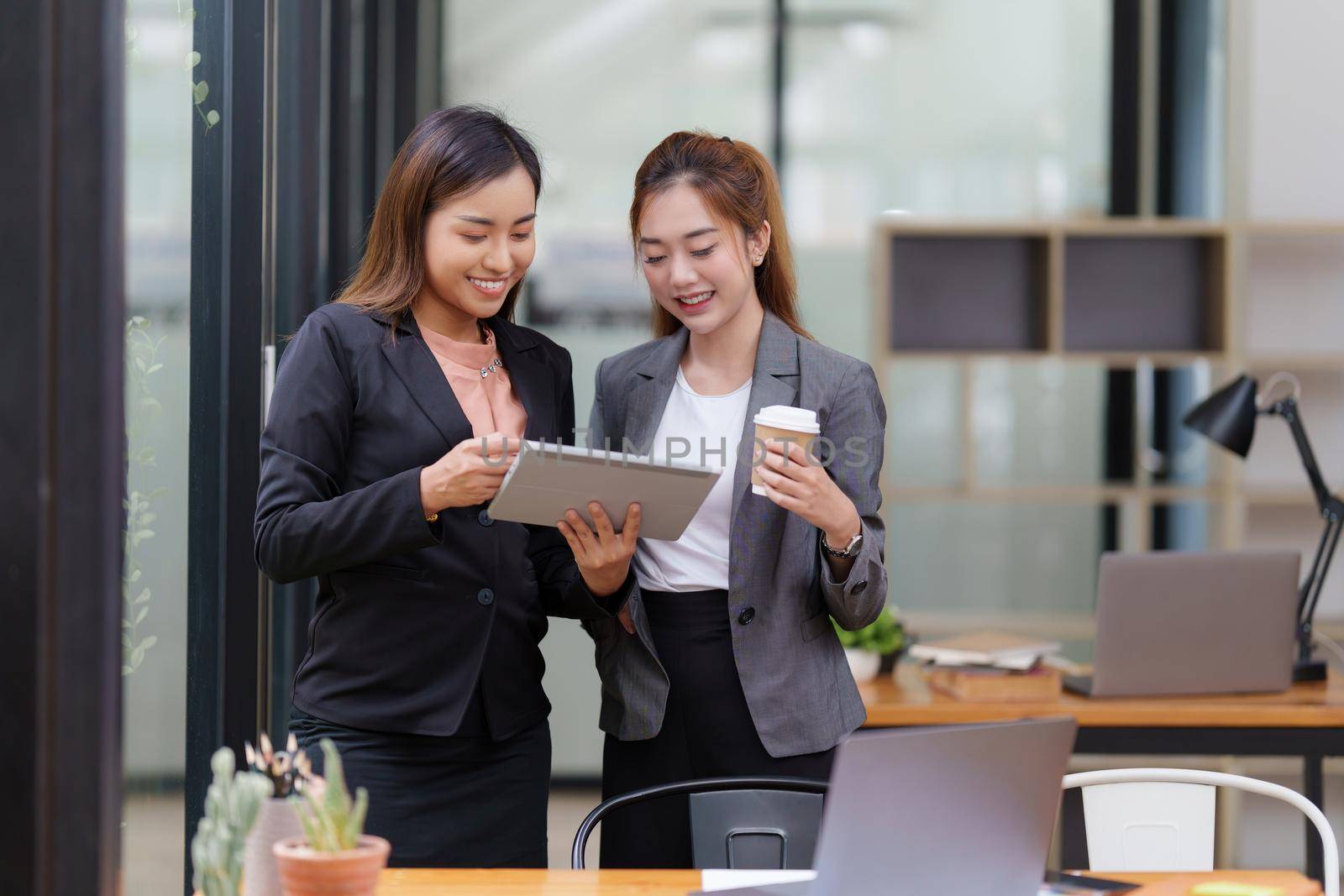Two Asian Business woman working and discuss by digital tablet at office.