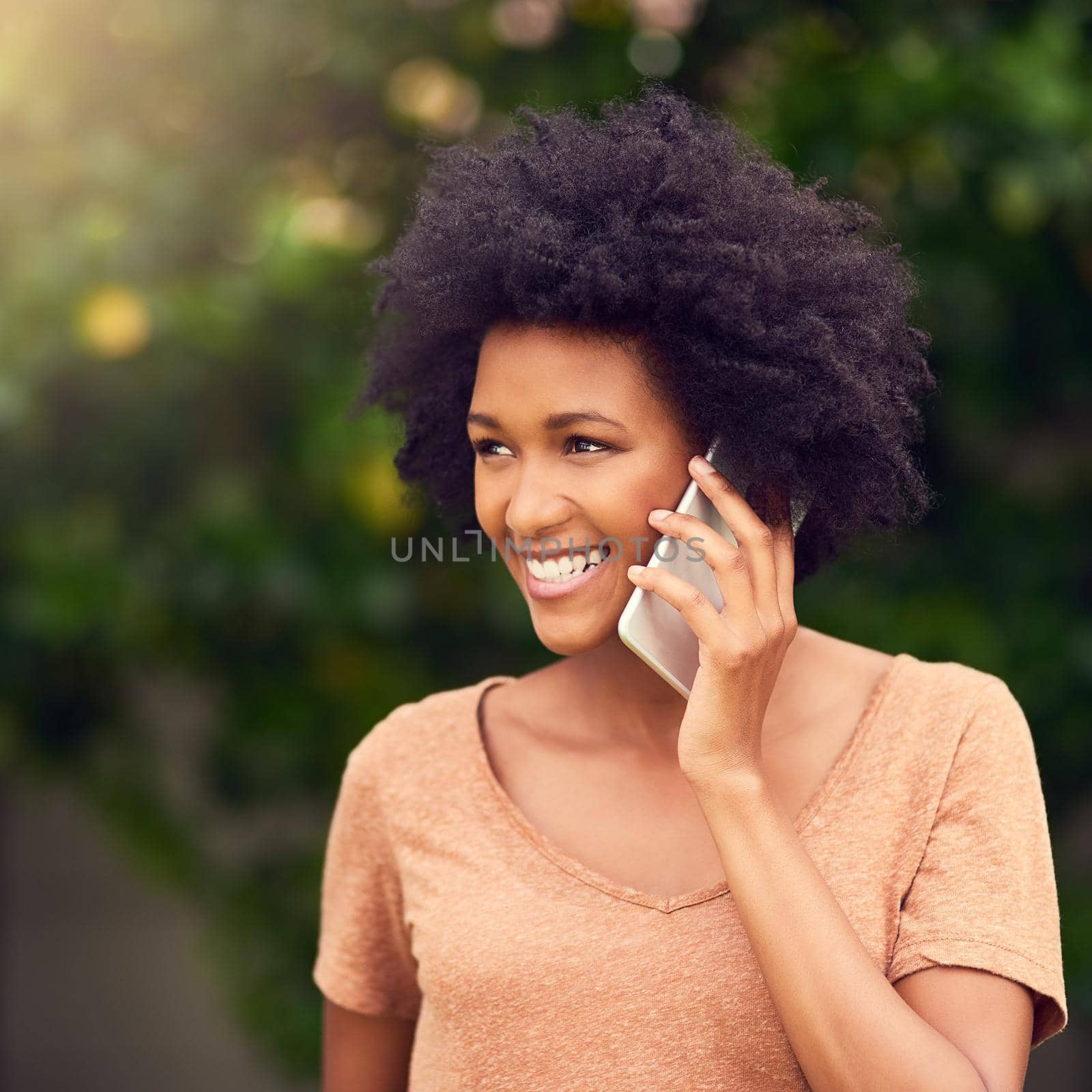 Are we still meeting at the park. a young woman talking on her cellphone while spending the day outdoors. by YuriArcurs