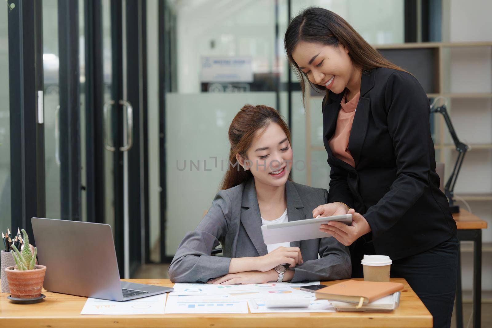 Two Asian Business woman working together by digital tablet at office.