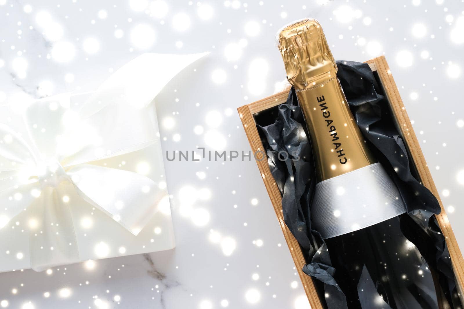New Years Eve, happy holidays and luxury present concept - Christmas holiday champagne bottle and a gift box and shiny snow on marble background