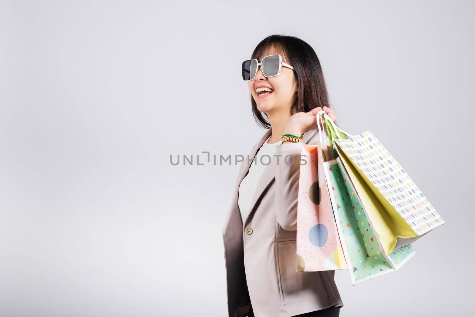 Happy woman with glasses confident shopper smiling holding online shopping bags colorful multicolor, Portrait excited Asian young female purchase studio shot isolated on white background, fashion sale