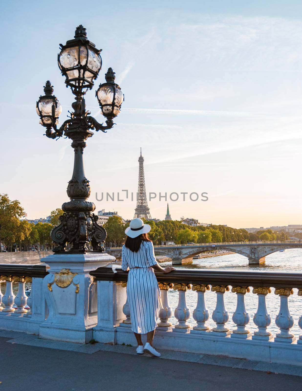 Young women with a hat viewing at the Eiffel tower from the Seine river, Alexander bridge Paris, view the famous landmark Alexander III bridge in Paris, the capital of France.