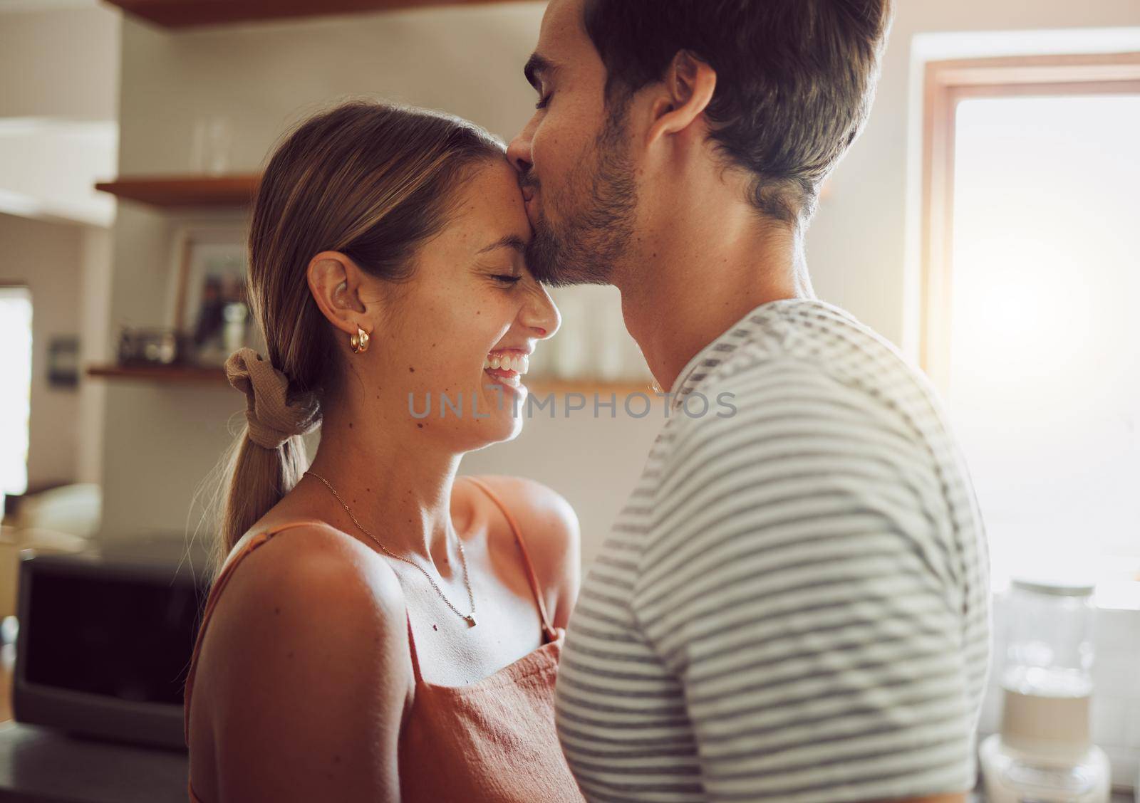 Affectionate, loving and romantic couple in a happy relationship together in the kitchen at home. Man and woman sharing a moment of happiness, romance and bonding with each other in love