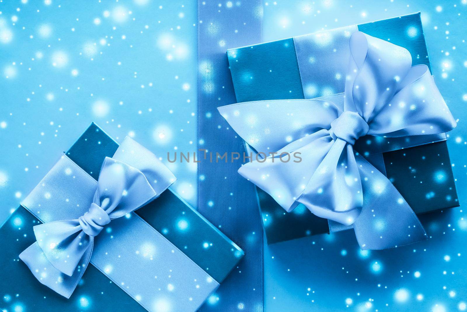 New Years Eve celebration, wrapped luxury boxes and cold season concept - Winter holiday gifts and glowing snow on frozen blue background, Christmas presents surprise