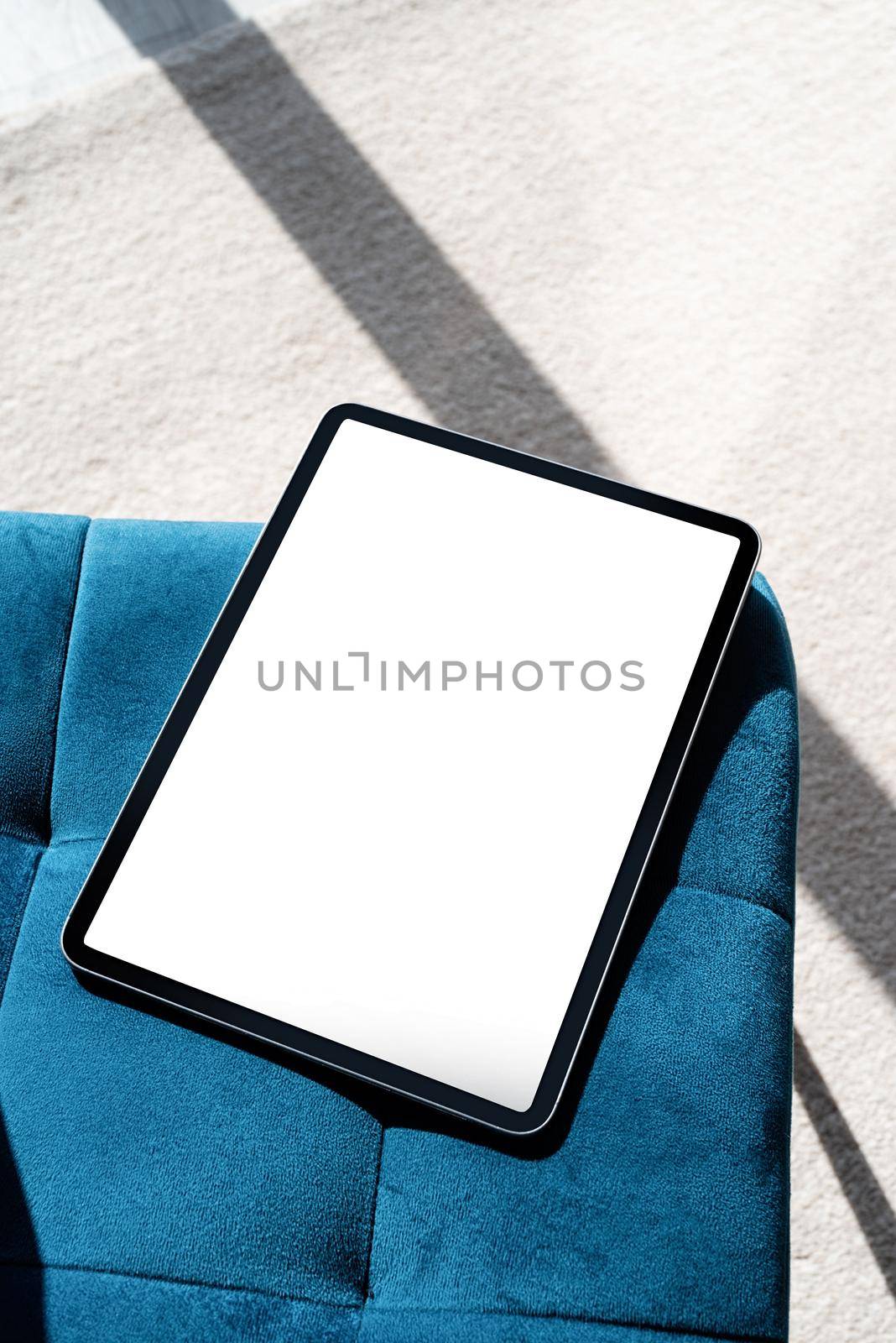 Digital tablet computer with isolated screen on blue chair for mockup design. At home interior.