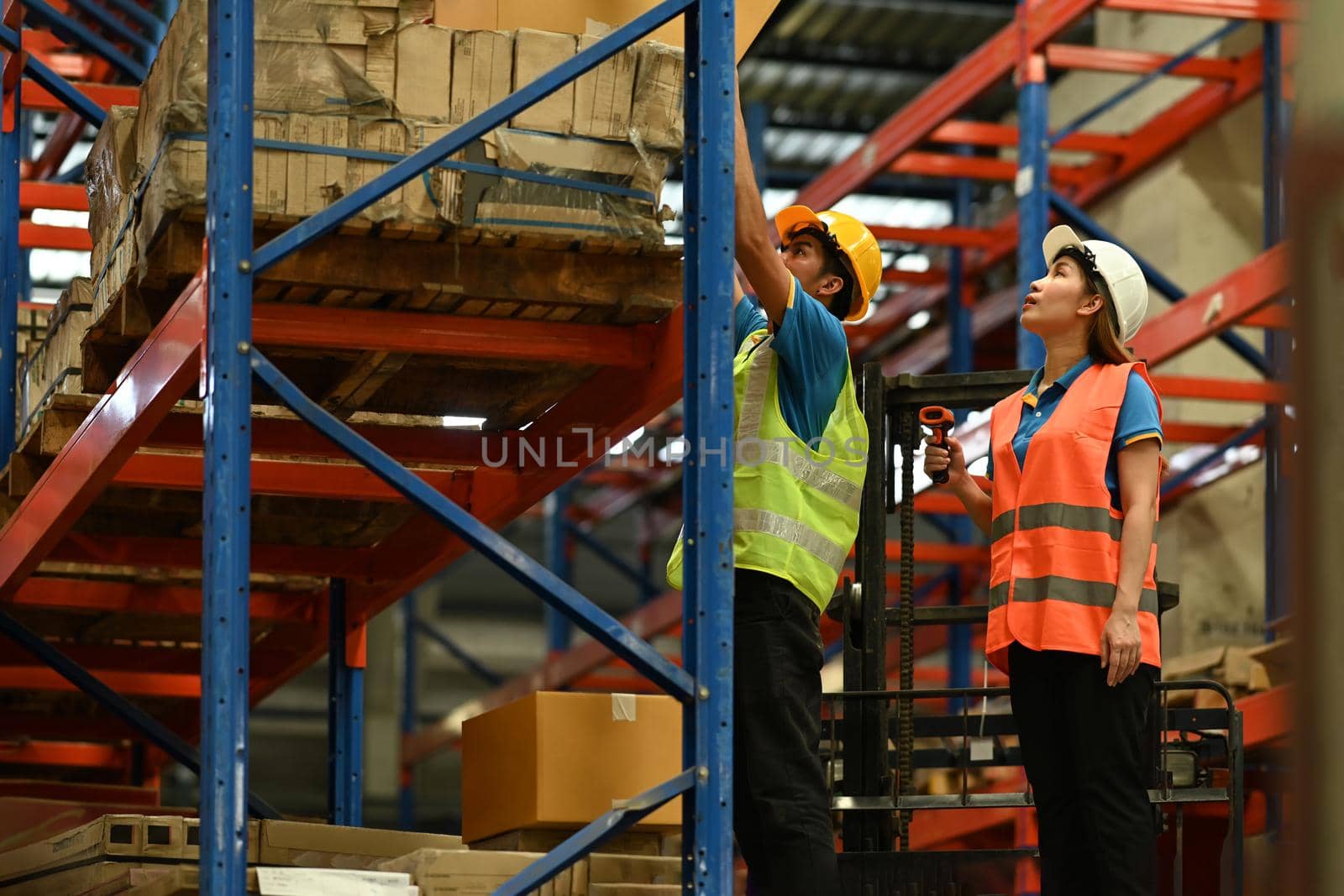 Shot of industrial workers checking inventory and quantity of storage product on shelf in a large warehouse.