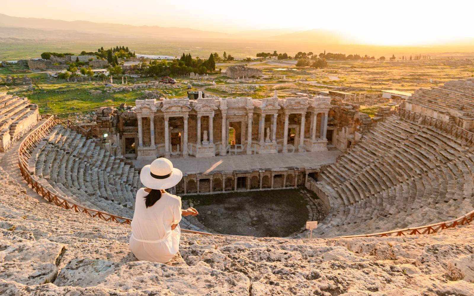 Hierapolis ancient city Pamukkale Turkey, young woman with hat watching sunset by the ruins Unesco by fokkebok