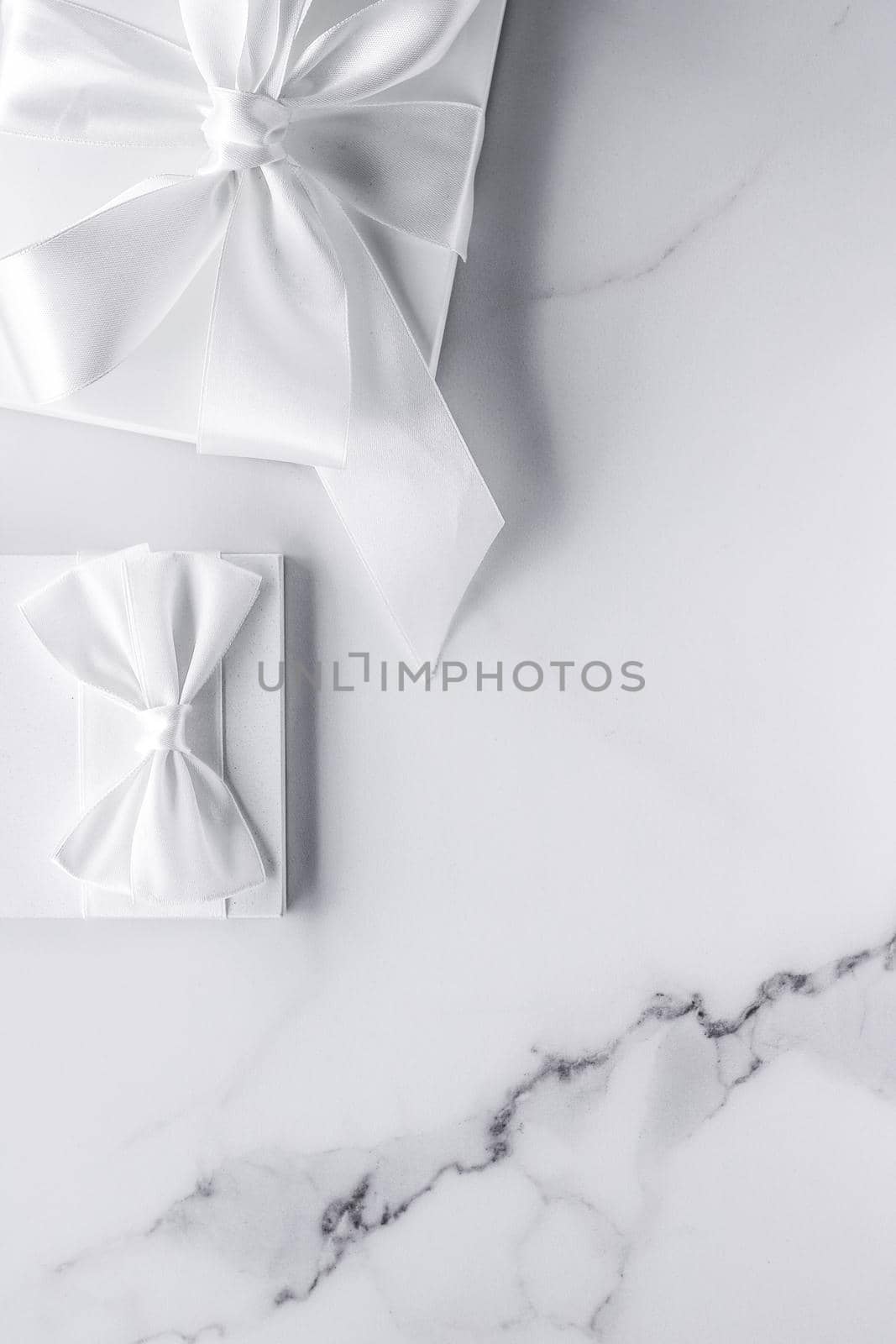 Luxury wedding gifts with silk bow and ribbons on marble background by Anneleven