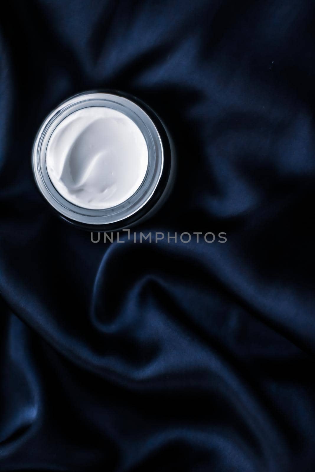 Luxury face cream jar on a dark blue silk by Anneleven