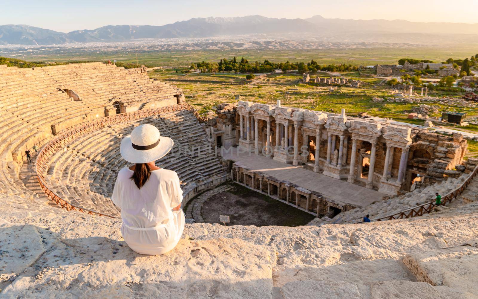 Hierapolis ancient city Pamukkale Turkey, young woman with hat watching sunset by the ruins Unesco by fokkebok