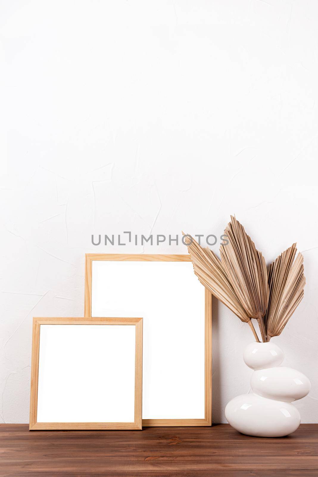 White frames mockup with dry palm leaves on wooden table in a vase , mockup design