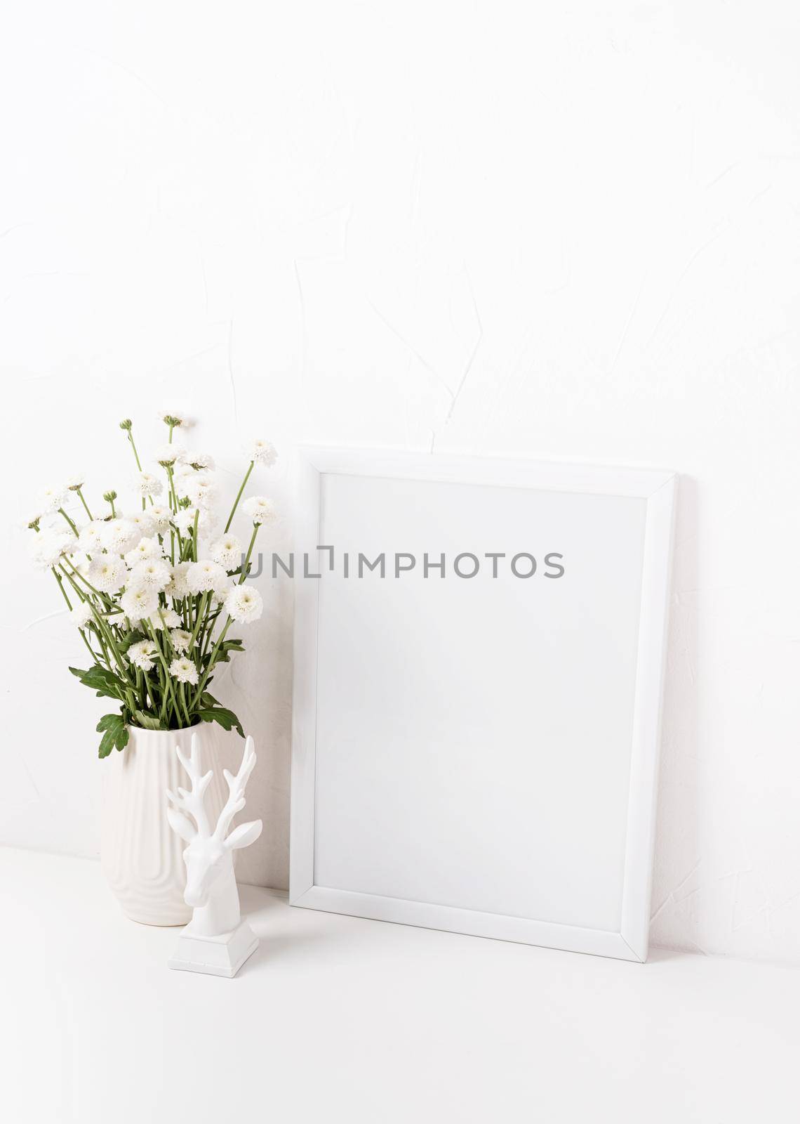 White frame mockup with chrysanthemum flowers in a vase on a white table, mockup design