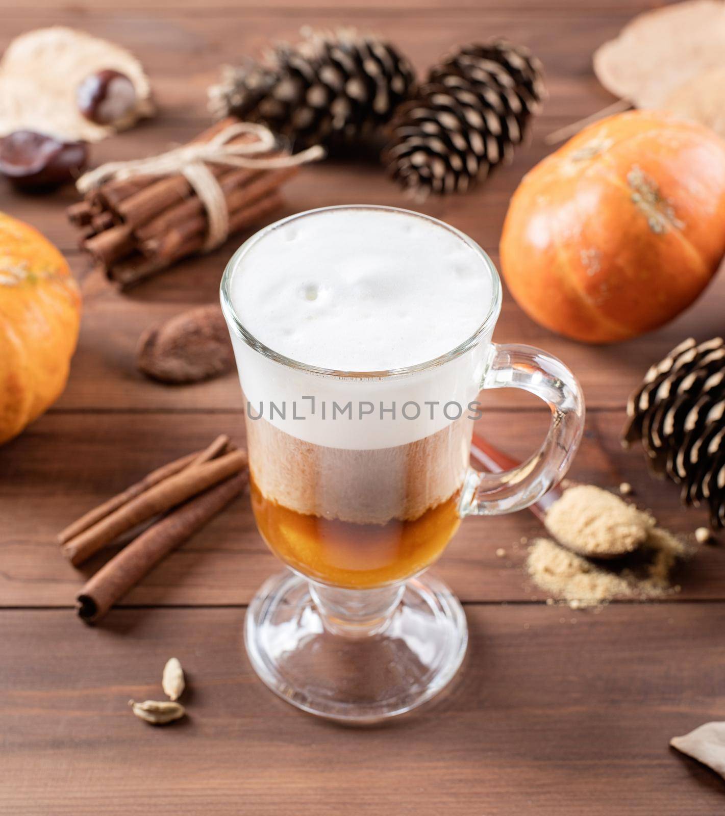 Autumn hot drinks. Pumpkin spice latte in a glass mug with cinnamon and ginger on wooden background with copy space