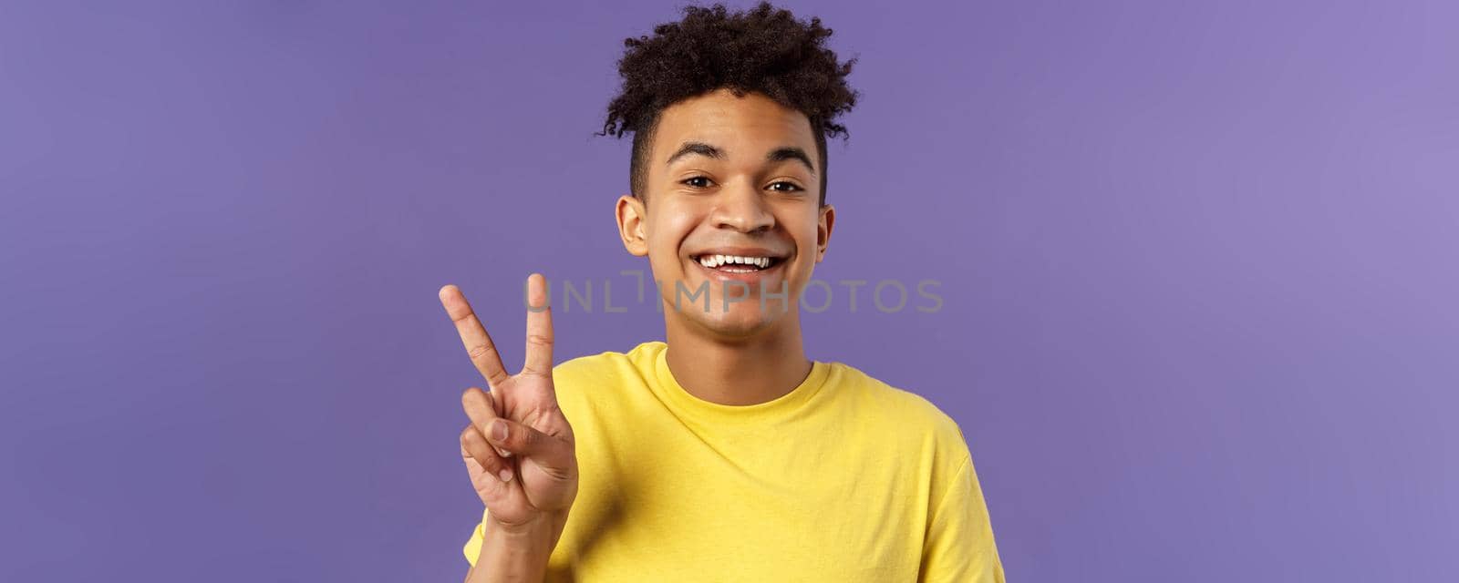 Close-up portrait of handsome upbeat young teenage guy with afro hairstyle, show peace sign and smiling, wear yellow t-shirt, staying optimistic and positive, purple background by Benzoix