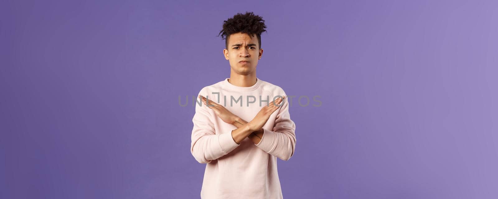 Portrait of young fed up man express his strong will to end this relationship, cross hands over chest in stop, enough gesture pouting and frowning, looking serious, disagree and prohibit action by Benzoix