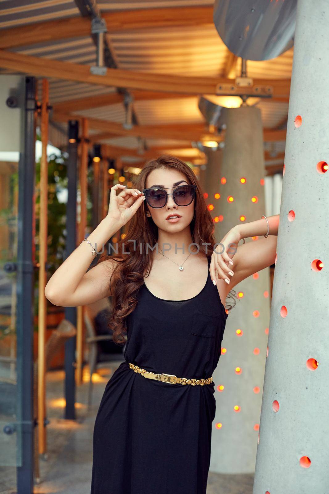 Close-up portrait of young elegant brunette in black dress and sunglasses. Fashion street shot by nazarovsergey