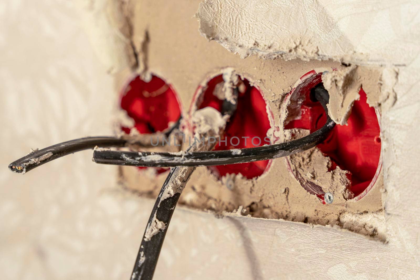 Installation of new electrical wiring, plastic sockets smeared with mortar and electrical wires for future sockets on a plastered wall, the concept of home renovation