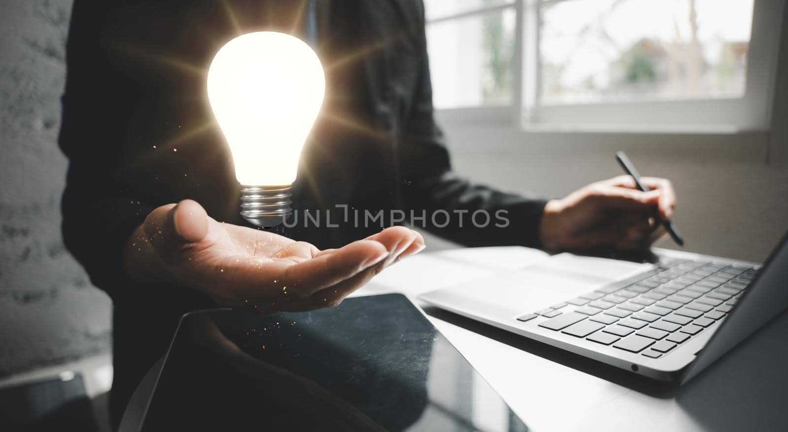 Business man working with laptop computer holding light bulb on hand by Sorapop