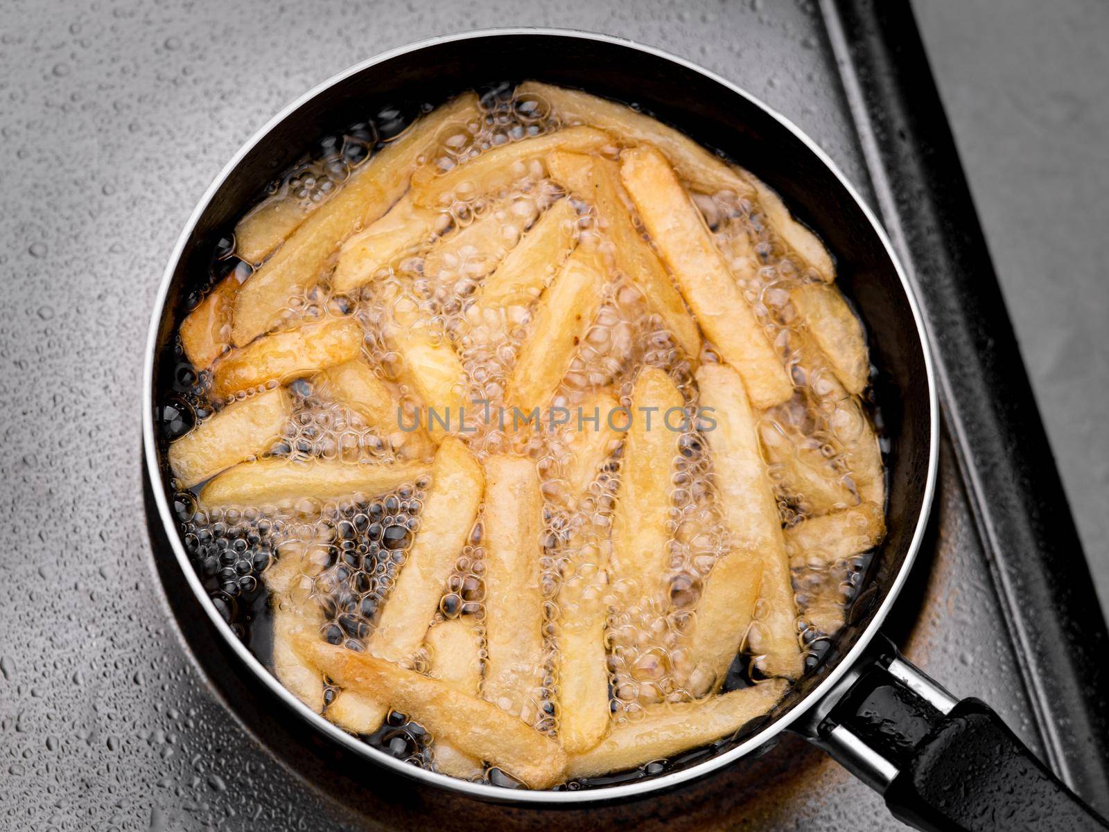 Close up of Frying french fries in the fryer in hot oil on the electric stove in the kitchen. Making homemade french fries.