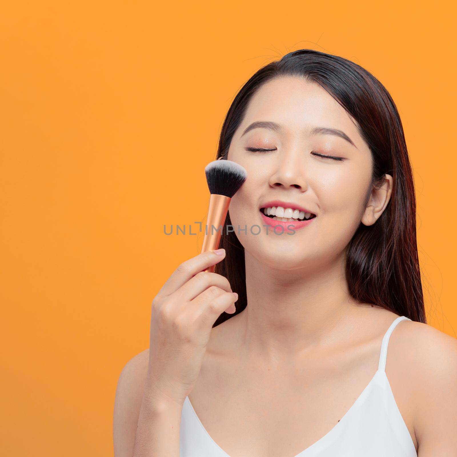 Beauty Asian Girl applying powder brush on her cheek by makidotvn