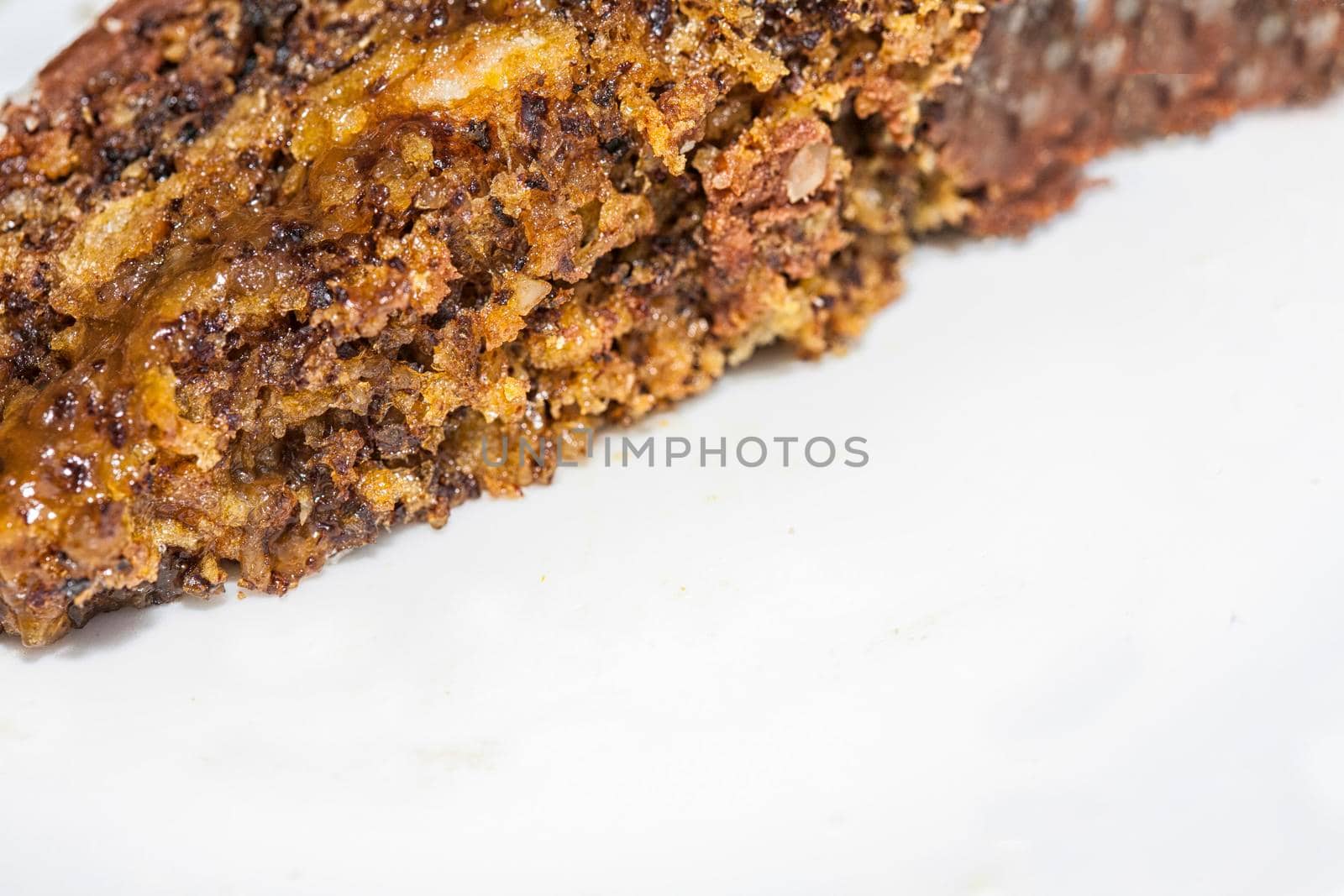 Close up view of a skice of brown, chocolate cake on a white plate. Chocolate crumbs can be seen on the plate.