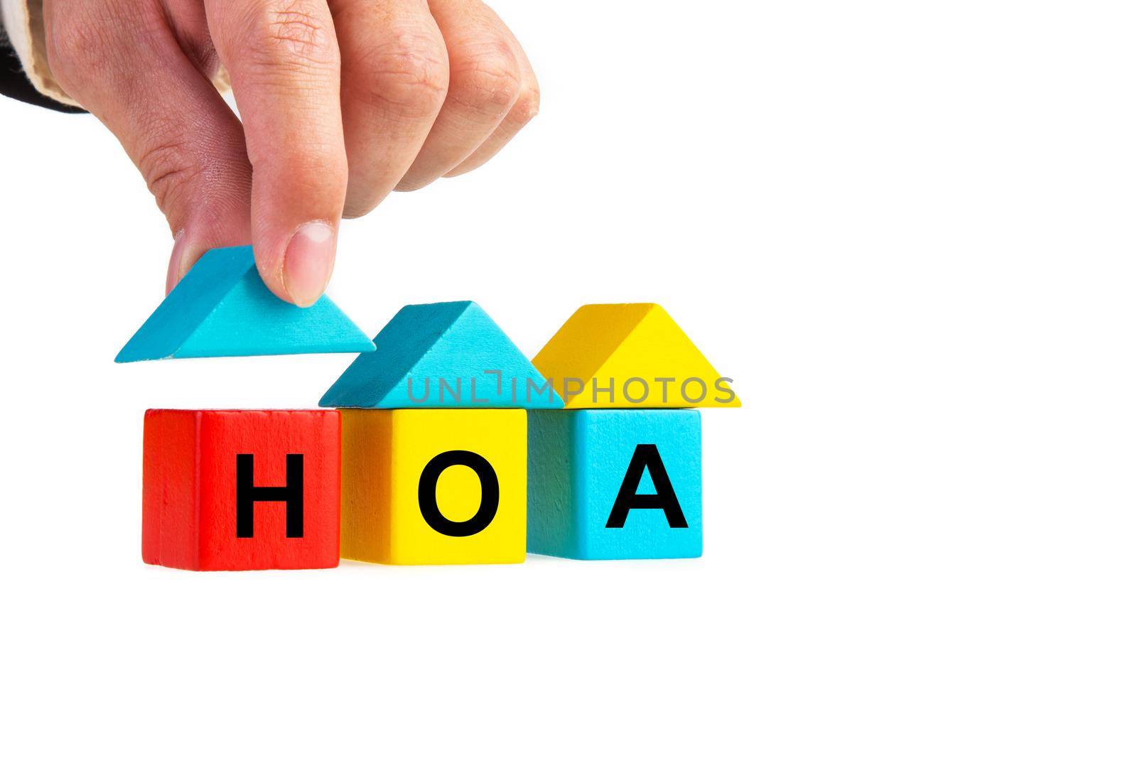 Businessperson's hand placing wooden house block with HOA word by tehcheesiong