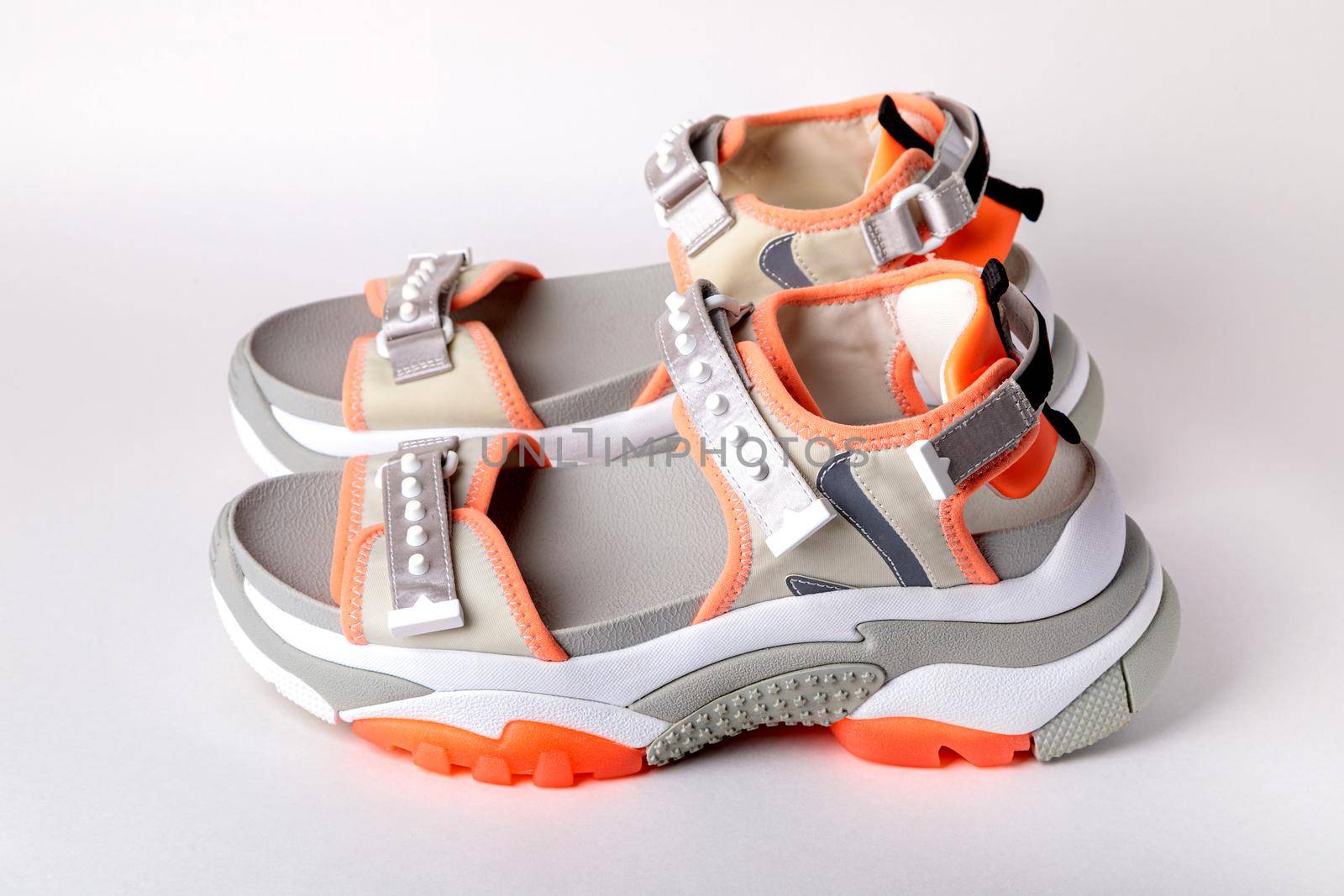 Women's, fashionable, sports sandals with orange accents on a white background. New youth shoes for girls. Side view