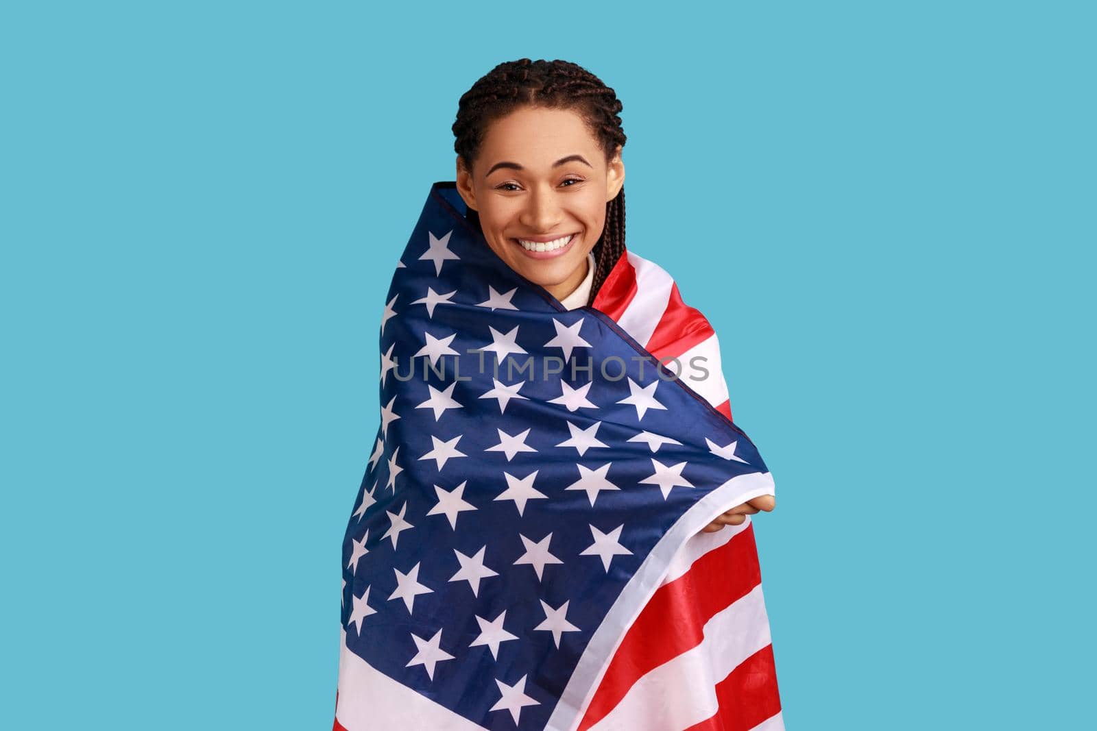 Woman standing wrapped in USA flag, celebrating national holiday, posing with toothy smile. by Khosro1