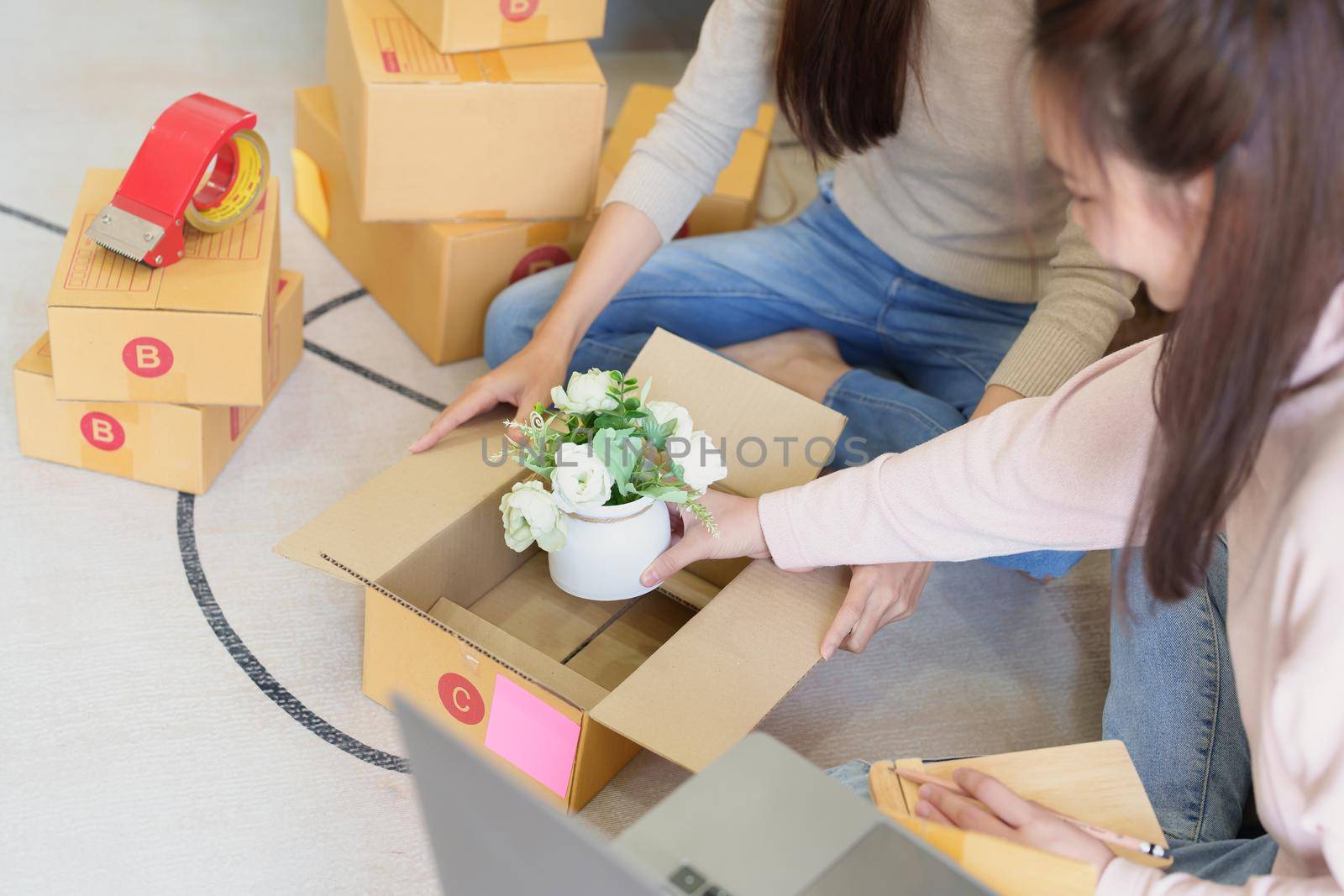 Starting small businesses, two Asian woman check online orders Selling products working with boxs freelance work at home office, sme business concepts
