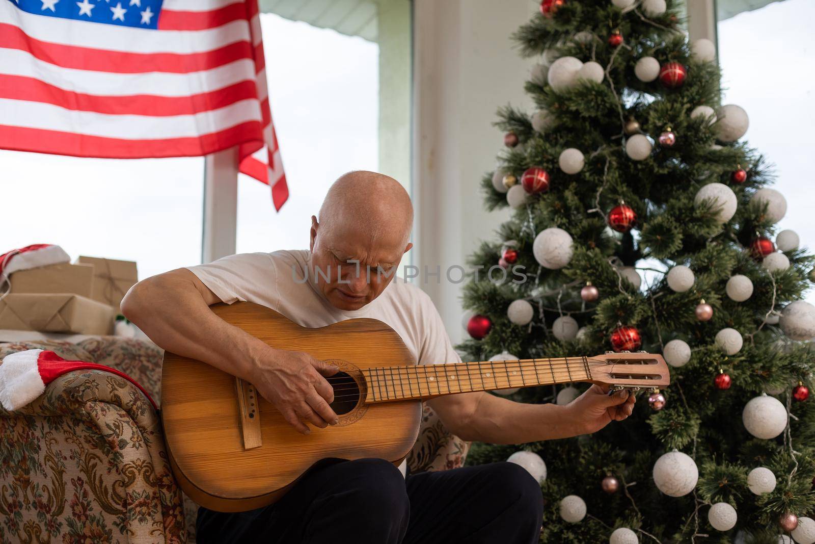 man holding guitar in front American Flag haning behind him at christmas by Andelov13